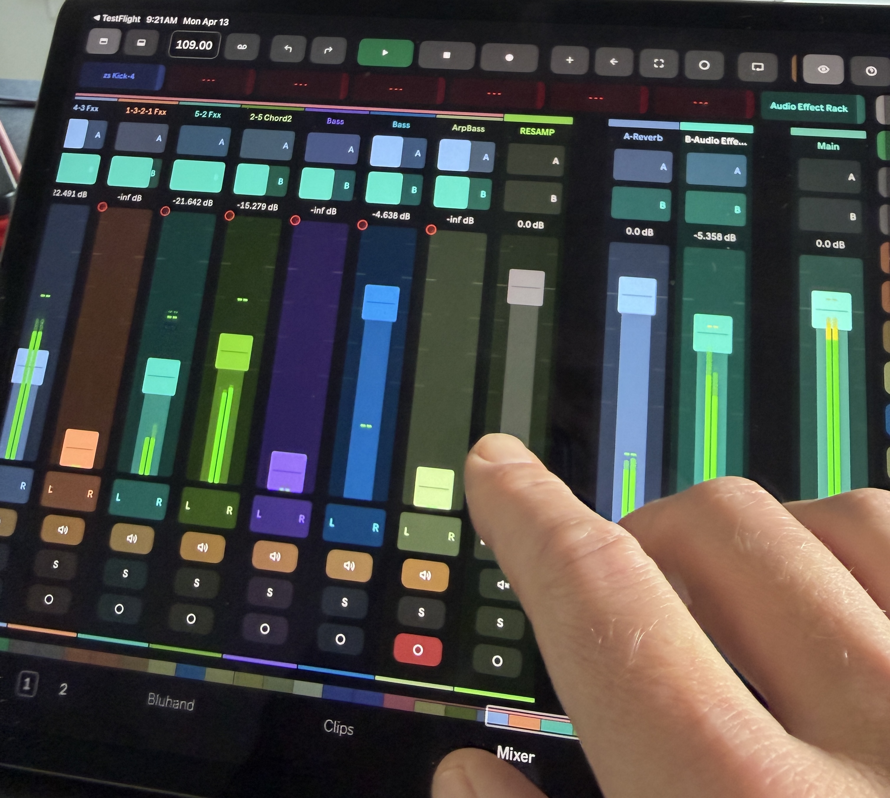 The Knobbler iPad app showing a colorful multi-track mixer with live audio meters next to each fader